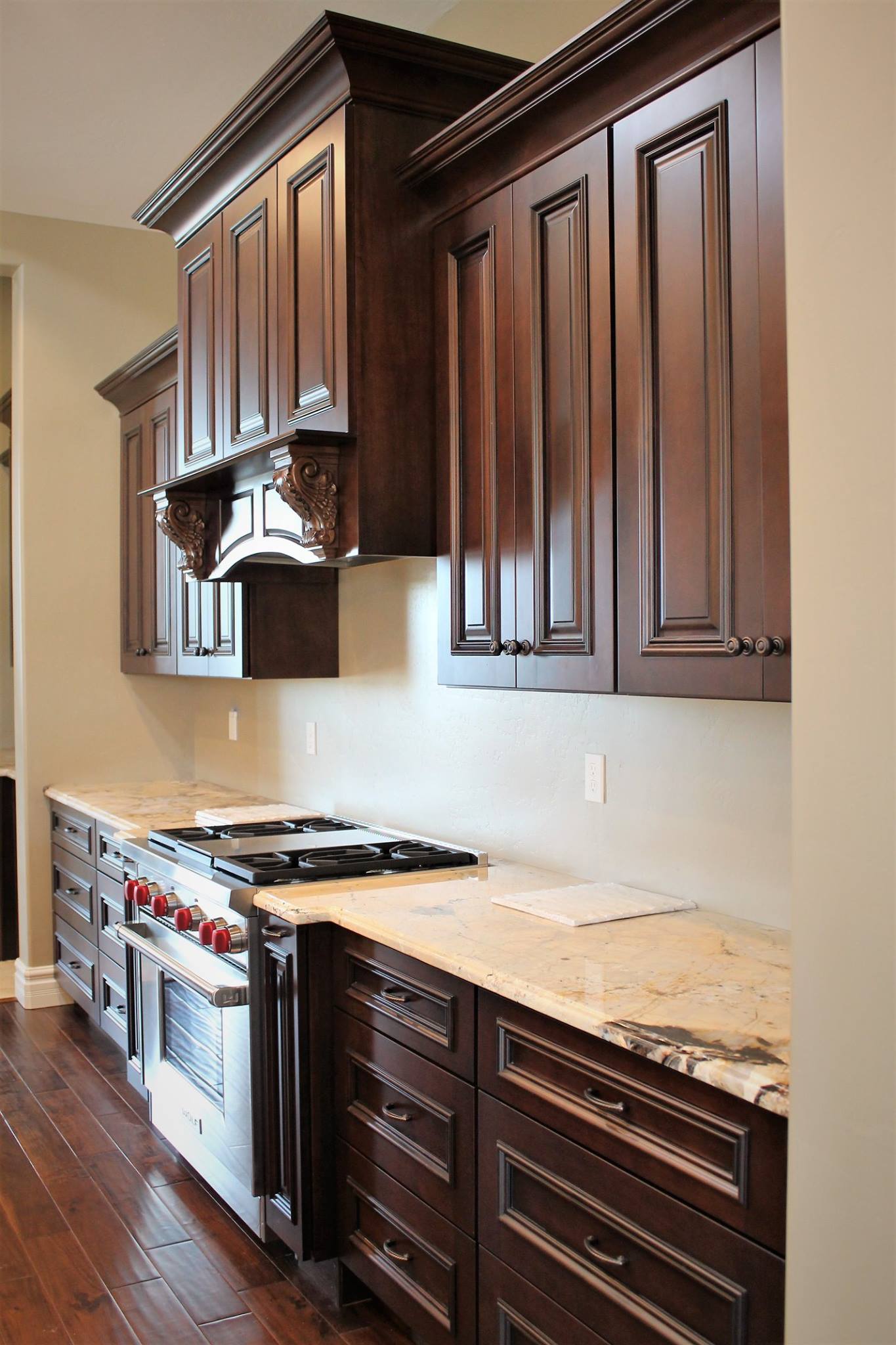 Kitchen renovation with dark stained cabinets, crown moulding, and marble countertops by Maverick Kitchens